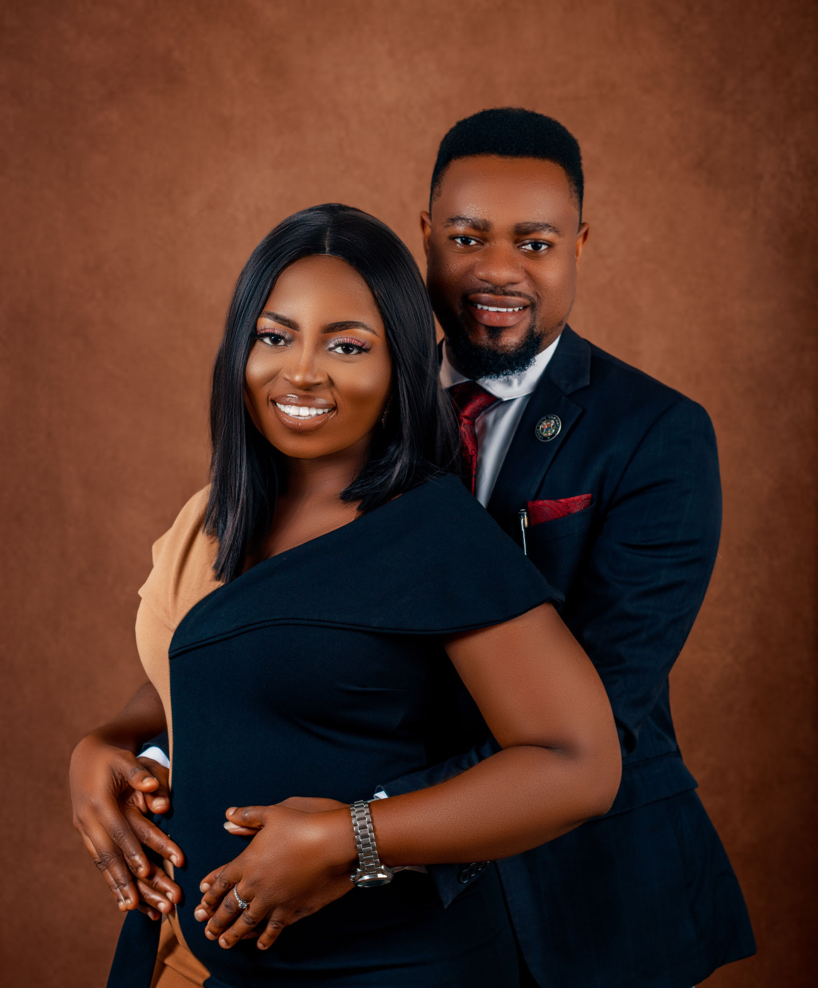 A couple photographed closely together against a brown studio backdrop, both faces visible