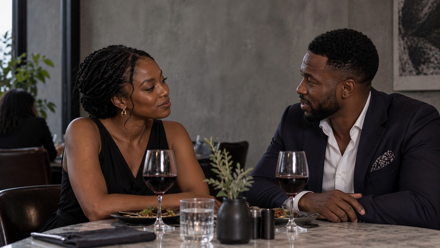 Two well-dressed adults in quiet conversation across a dinner table